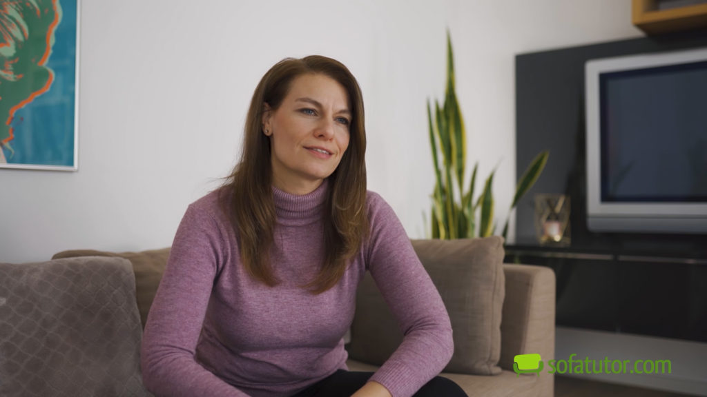 Frau sitzt lächelnd zu Hause auf dem Sofa. Thumbnail eines Werbevideos für die sofatutor GmbH.